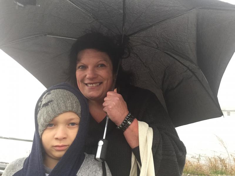 Marquise Sweek, 10, of Topsham and his grandmother Judy Normand of Litchfield share an umbrella after getting off a Maine Eastern Railroad passenger ride to Wiscasset Oct. 25. SUSAN JOHNS/Wiscasset Newspaper