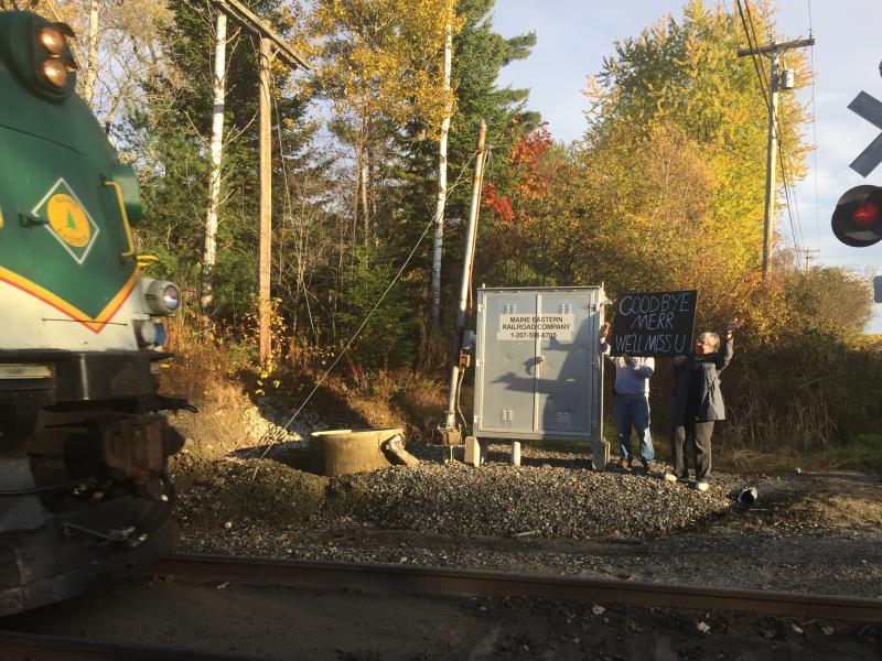 Maine Eastern Railroad’s final passenger excursion run nears Old Ferry Road in Wiscasset Sunday afternoon as Gordon and Lynne Kontrath, neighbors of the tracks, wave and hold up a goodbye sign. SUSAN JOHNS/Wiscasset Newspaper