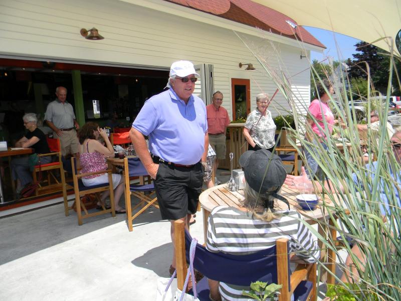 Oliver's proprieter Paul Coloumbe, center, greets customers on July 13 while he waits for his haddock taco to be served. At Oliver's, customers have three different choices for seating: on the dock, inside or upstairs on the porch. DIANE RANDLETT/Boothbay Register DIANE RANDLETT / Boothbay Register Paul Coloumbe Oliver's Cozy Harbor wharf