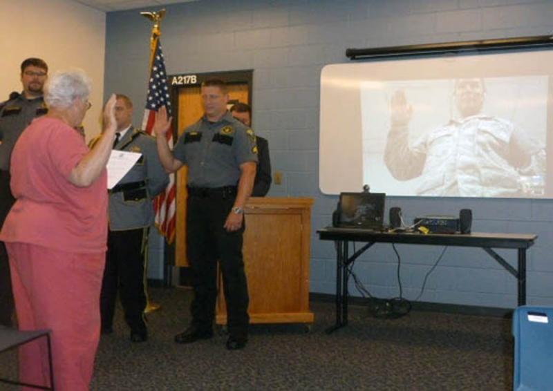 Jail Authority Clerk Katharine Martin-Savage swears in newly promoted officers at the Promotion Ceremony held at the Two Bridges Regional Jail. Sergeant Richard Wardwell, seen on the projection screen on the right, participated in the ceremony through Skype from Abu Dhabi in the United Arab Emirates where he is currently deployed as a member of the National Guard. Photo Courtesy of Two Bridges Regional Jail