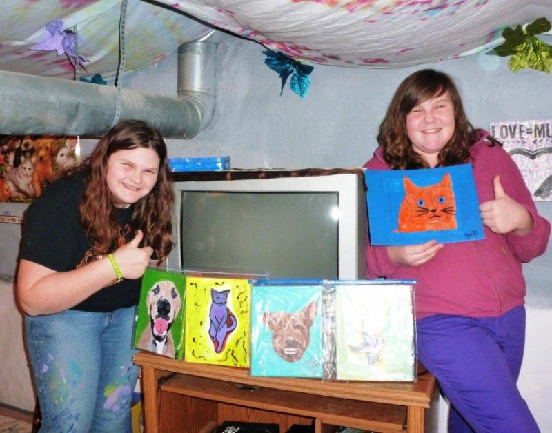 Tabetha Harrington, left, and Chelsie Graves in “Tab’s Cool Cave” basement studio. Below: This happy pup was the very first painting Tabetha completed. It currently hangs in her studio. KATRINA CLARK/Boothbay Register Tabetha Harrington, left, and Chelsie Graves in “Tab’s Cool Cave” basement studio. KATRINA CLARK/Boothbay Register