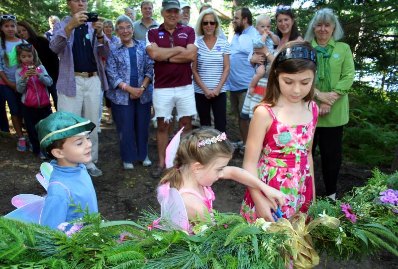 Cutting the beribboned garland at Saturday’s grand reopening of the shorefront Fairy House Village are twins Ronan and Maeve Cullina (age 5) and, at right, Brooklyn Cone (8-1/2). Stone “ruins” and other imaginative structures by Joe Norton add a touch of magic to the Village where visitors at the celebration sprinkled fairy dust, conjured up elaborate fairy houses and made cupcakes disappear. Courtesy of Barbara Freeman Cutting the beribboned garland at Saturday’s grand reopening of the shorefront Fairy House Village are twins Ronan and Maeve Cullina (age 5) and, at right, Brooklyn Cone (8-1/2). Stone “ruins” and other imaginative structures by Joe Norton add a touch of magic to the Village where visitors at the celebration sprinkled fairy dust, conjured up elaborate fairy houses and made cupcakes disappear. Courtesy of Barbara Freeman
