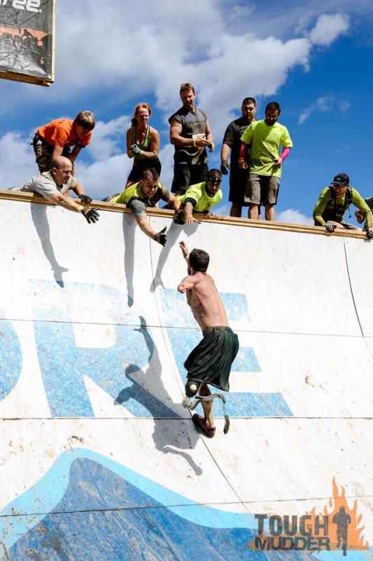 Wounded warrior Noah Galloway soars up “Everest” as Jason Nein (left) and Jared Mitkus (with mohawk) reach down to help him over. Karen Colby stands directly behind Mitkus. Courtesy of Tough Mudder photographer, Dmitry Gudkov. Wounded warrior Noah Galloway soars up “Everest” as Jason Nein (left) and Jared Mitkus (with mohawk) reach down to help him over. Karen Colby stands directly behind Mitkus. Courtesy of Tough Mudder photographer, Dmitry Gudkov.