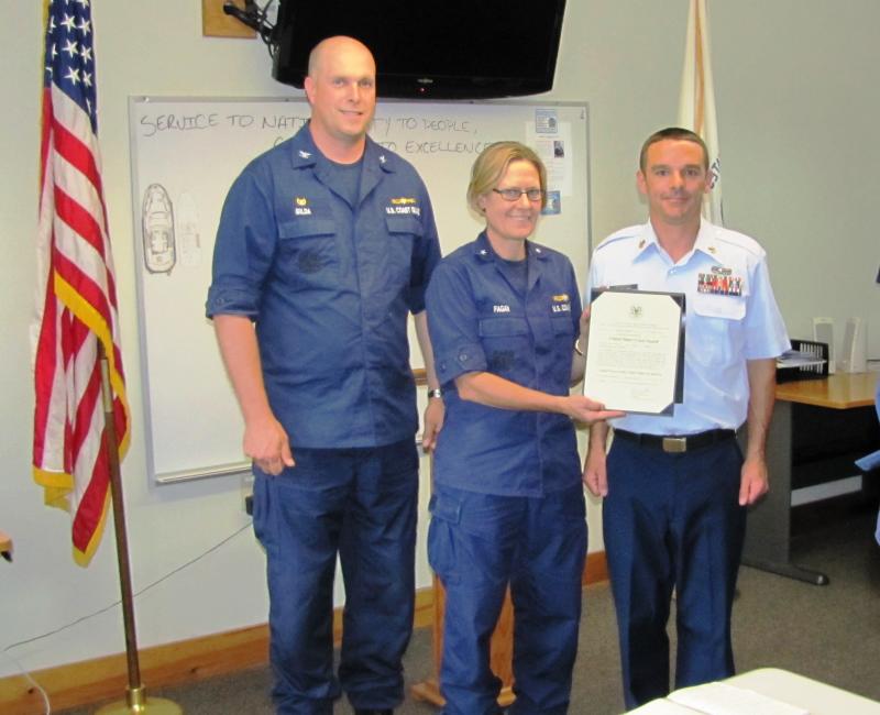 Rear Admiral Linda Fagan, center, newly appointed Commander of USCG First District, joined by Capt. Brian Gilda, left, completes the advancement of station member Tony Shumpert to Boatswain Mate First Class by presenting him with his advancement certificate. The ceremony includes the pinning on of the collar devices showing the new rank and the reading of the certificate. Courtesy of Ted Chatham/USCG Auxiliary