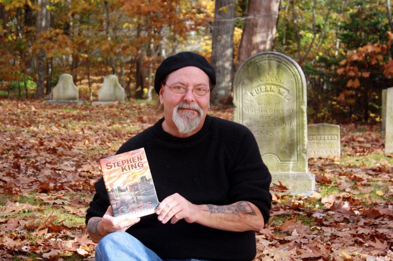 NEAR BOOTHBAY HARBOR’S Pear Street Cemetery on Oct. 30, Glenn Chadbourne holds a just-published collector’s edition of Stephen King’s “Carrie,” illustrated by Chadbourne. SUZI THAYER/Boothbay Register