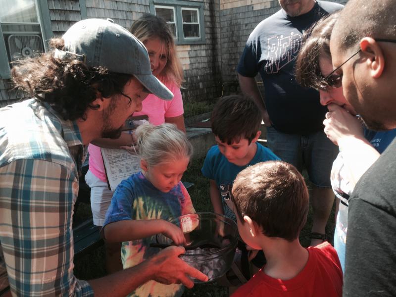 Morris Farm educator John Affleck holds a bowl of ice cubes with flowers inside them, during an Aug. 6 celebration of learning for the Wiscasset School Department’s summer program. Showing interest are Kylee Smith, 7, left, and Hunter Giroux, 6, both of Wiscasset. SUSAN JOHNS/Wiscasset Newspaper John Affleck, Morris Farm, Kylee Smith, Hunter Giroux