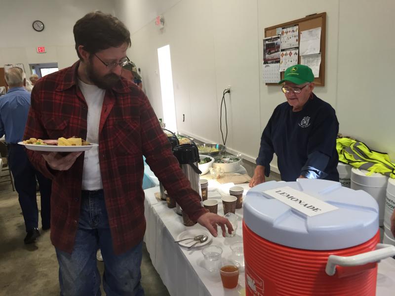 Newcastle’s James Patten, left, with a plate of ham and fixings, picks up a beverage before heading for one of the long tables set up inside the station’s bay. On the other side of the beverages lineup was volunteer Herman Lovejoy, one of the department’s safety officers. His wife and fellow department member Marcie Lovejoy, along with fellow safety officer Jim Bruce, joined him in manning the beverages. SUSAN JOHNS/Assistant Editor James Patten, Herman Lovejoy, Alna Fire Department