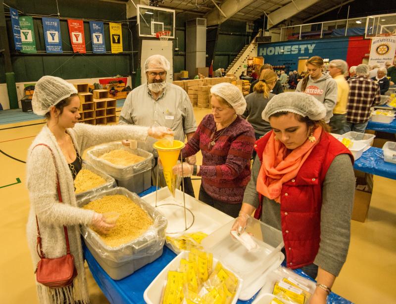 Tom Dewey and pastor Sarah Foulger of Boothbay Harbor's Congregational Church (center left and center right) on the assembly line at Sunday's "End Hunger in New England" event, a joint venture between the Boothbay Harbor Rotary and Damariscotta-Newcastle Rotary clubs to package food packets for needy area families. Courtesy of Steve Demeranville