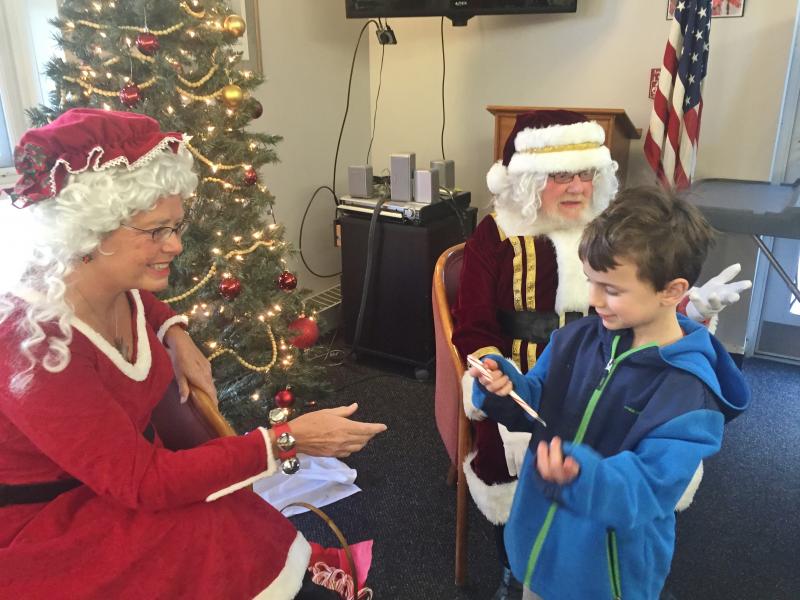 Kayden Reith, 6, of Dresden accepts a candy cane Dec. 19 at Wiscssset Community Center from Mrs. Claus, a.k.a., Mattie Welch of Jefferson as Santa Claus, a.k.a. Nim Welch motions for the next child in line to come forward. SUSAN JOHNS/Wiscasset Newspaper