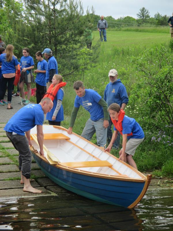 Kurt Spiridakis, Maine Maritime Museum boatshop manager and student advisor, is shown on the left lending a hand with the launch of one two skiffs built by Woolwich Central School seventh and eight graders. PHIL DI VECE/Wiscasset Newspaper