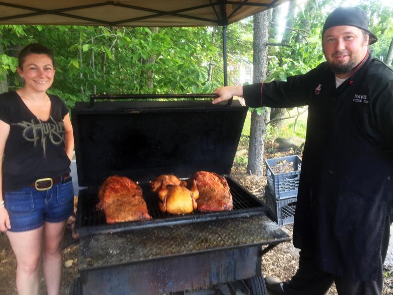 Christie and Travis Benner check on the smoked beef brisket and chicken that cooks all day behind their food stand. SUZI THAYER/Boothbay Register