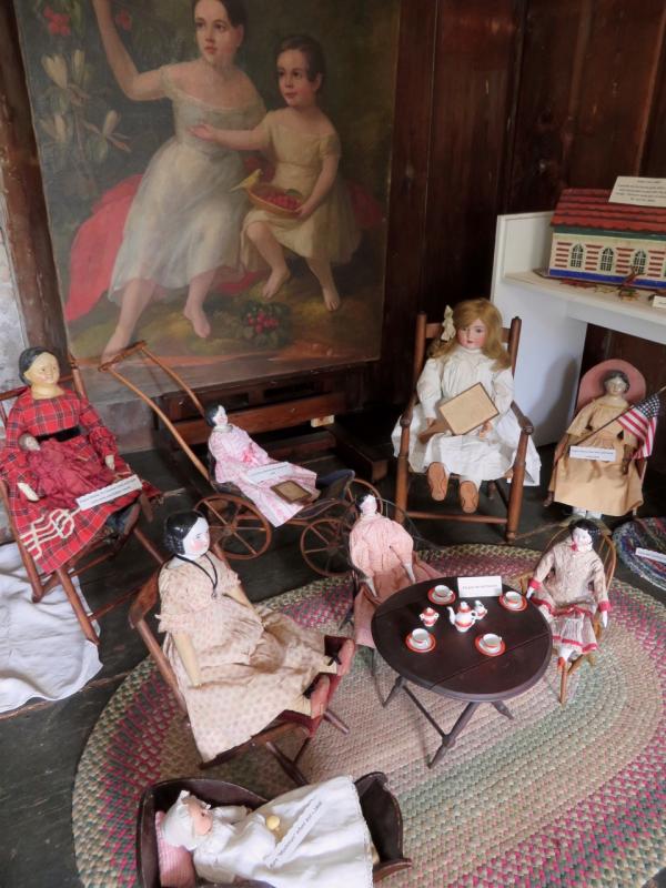 A selection of dolls arranged before a painting of children who lived at the Pownalborough Court House in the mid-1800s were common over the course of nearly 100 years.Courtesy photo