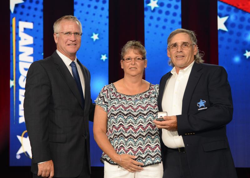Landstar President and CEO Jim Gattoni, left, presents Woolwich’s Joe Westleigh with an award at Landstar’s All-Star Celebration in Nashville, Tennessee. Westleigh’s wife Melisa joins in the ceremony on-stage. Courtesy of Landstar System