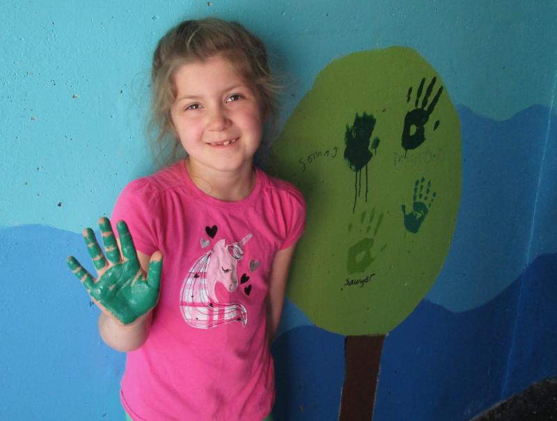 Georgia Leeman takes part as Woolwich Central School’s first and fourth graders apply the finishing touch to students' mural in the pedestrian tunnel. The entire K thru eighth grade student body took part. PHIL DI VECE/Wiscasset Newspaper