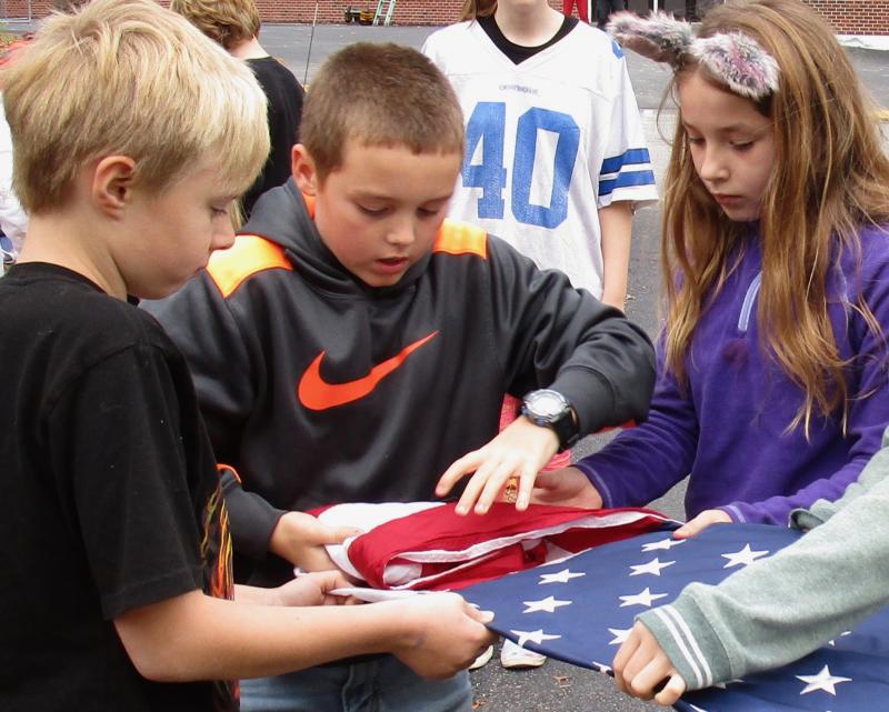 Carefully folding the American flag into a triangle are, from left, Wiscasset Elementary School fifth graders Alex Akers, Noah Ruzyckij and Gabby Dodson. PHIL DI VECE/Wiscasset Newspaper