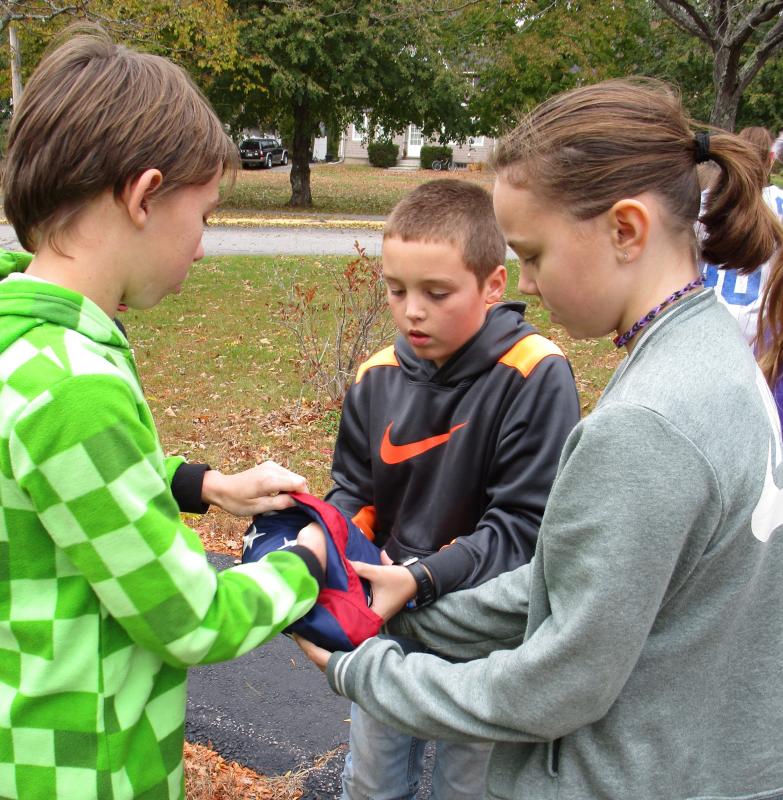 Garrett Marshall, Noah Ruzyckij and Kasey Pinkham finish folding the flag by tucking its corner inside. PHIL DI VECE/Wiscasset Newspaper