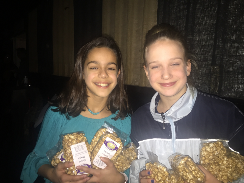 Sophia Scott, left, and Lily Nein handing out bags of Coastal Maine Popcorn’s gourmet Maine maple popcorn