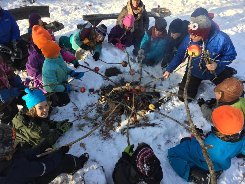 Gathered around a campfire, students roast local apples on their own hand-carved roasting sticks. Courtesy of Juniper Hill School