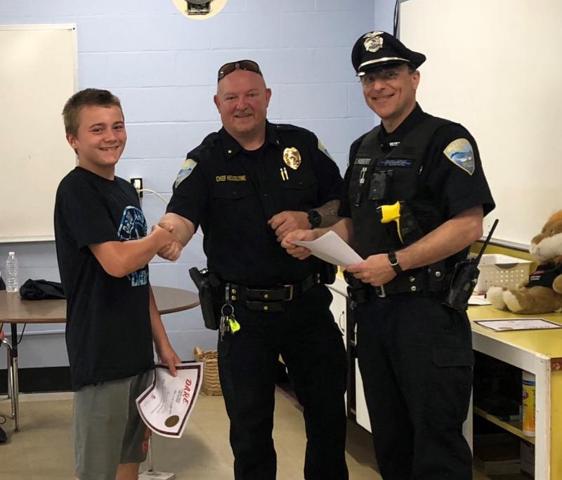 Chief Larry Hesseltine and SRO Cory Hubert hand out a certificate to fifth grade DARE graduate Steven Lutes. Cindy Collamore photo