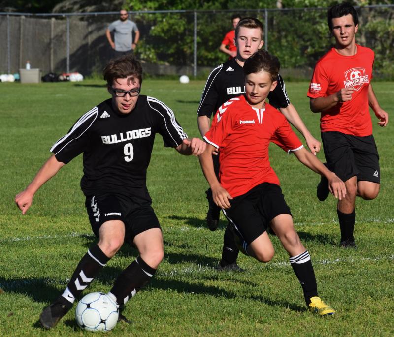 Wiscasset’s Emmit Loupe, right, flanked by defender Matt Eckert, pursues Hall-Dale’s Camden Adam. Adam scored three goals in the first half. PHIL DI VECE/Wiscasset Newspaper