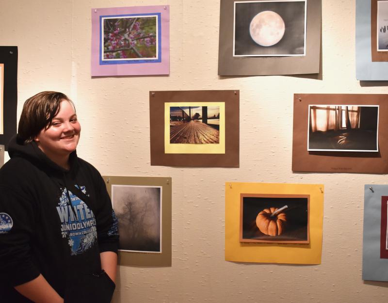 Ellery Downing stands alongside digital photographs by WMHS students. PHIL DI VECE/Wiscasset Newspaper