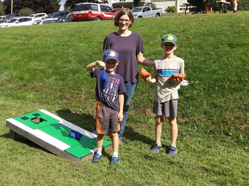 Maureen Cooper referees the bean bag toss for sons Sam, left, and John. JANE CARPENTER/Boothbay Register