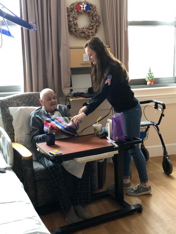 WMHS junior and student council member Gwen Webber presents a veteran with a lap blanket. Courtesy of Deb Pooler