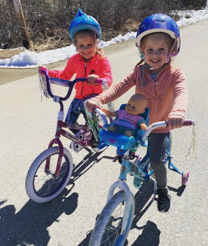 Identical Wiscasset twins Kamryn, left, and Addyson Petrie, 4, ride bikes around the neighborhood. Courtesy of Julie Petrie