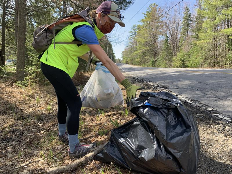 Alna’s Maria Jenness reaches for a trash bag she was filling on Route 218 April 24 in the town-wide roadside cleanup she organized. SUSAN JOHNS/Wiscasset Newspaper