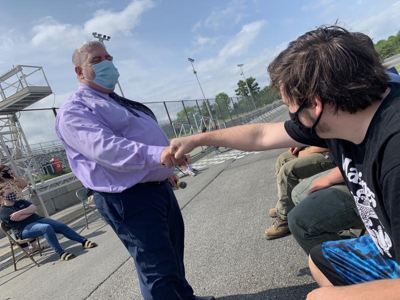 WMHS Principal Charles Lomonte and senior Kasey Mills bump fists at marching practice at Wiscasset Speedway June 9. Mills told Wiscasset Newspaper he was excited and happy for graduation. SUSAN JOHNS/Wiscasset Newspaper