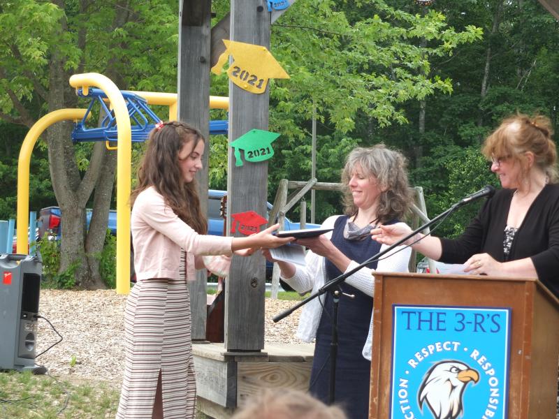 It was a big day on June 14 for Eva Whitmore. She graduated sixth grade and received two awards. Here she is receiving the Arts Award from music teacher Jennifer McIvor, center, and integrated arts teacher Robin MacCready. BILL PEARSON/Boothbay Register