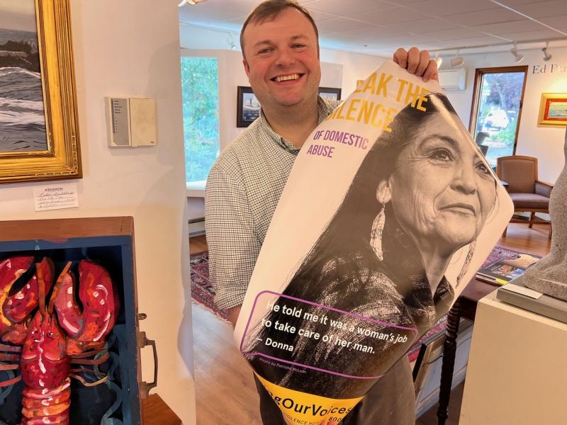 Andrew Gleason of Gleason Fine Art accepts a new FOV poster. Gleason’s is one of the businesses in town that never removed the original poster two years ago. Patrisha McLean photo