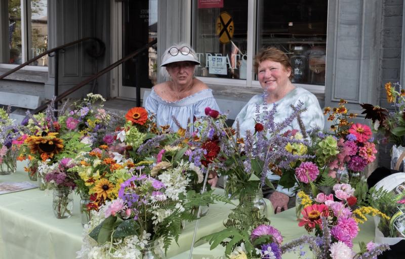 GCW table 2021: During the Wiscasset Art Walk, fresh bouquet organizers Terry Heller, left, and Jan Flowers, greet visitors and raise funds for local high school students. Bob Bond photo