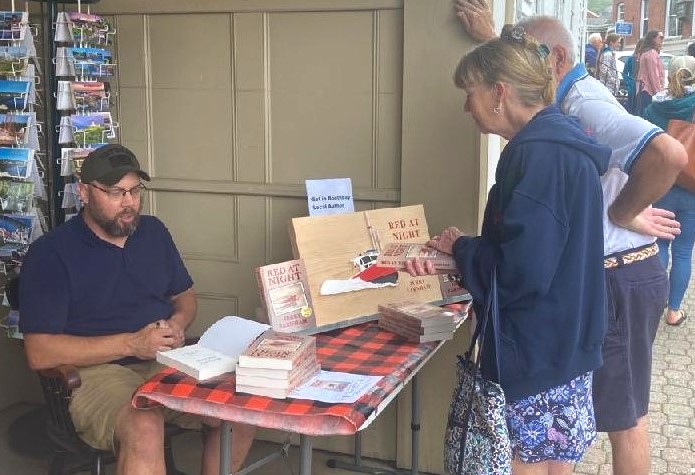 Author Jerry Farnham outside Sherman’s Bookstore in Boothbay Harbor signing copies of his first novel, “Red At Night,” during the annual Windjammer Days Festival in late June last year. Courtesy of the author
