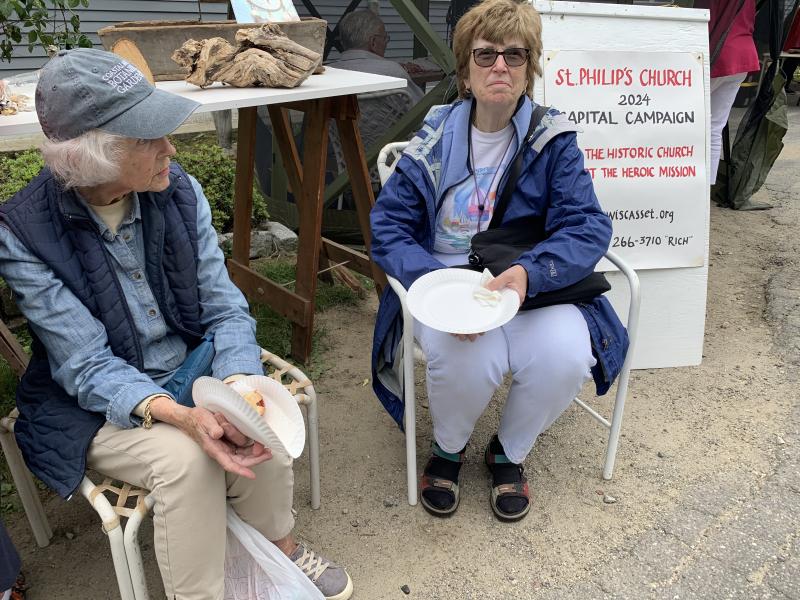 Boothbay neighbors Jane Hamilton and Ginny Baden finish hot dogs while sitting in chairs that made their first time at the Strawberry Festival also a successful shopping trip. SUSAN JOHNS/Wiscasset Newspaper