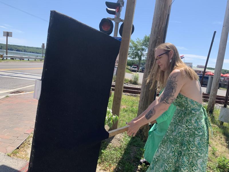 Heather Jones moves a covering away after helping unveil one of the signs. SUSAN JOHNS/Wiscasset Newspaper Ceremony