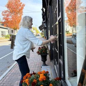Surrounded by the fiery colors and reflections of the season, Ann Scanlan arrives at her Sylvan Gallery on Water Street, Wiscasset Friday morning, Oct. 2. SUSAN JOHNS/Wiscasset Newspaper 