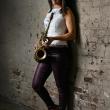 Vanessa Collier standing on wall with saxaphone