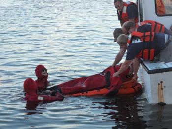 Members of the Wiscasset Fire Department, clad in bright red Gumby suits, conduct a water rescue training exercise on the town's waterfront August 22. JOHN MAGUIRE/Wiscasset Newspaper