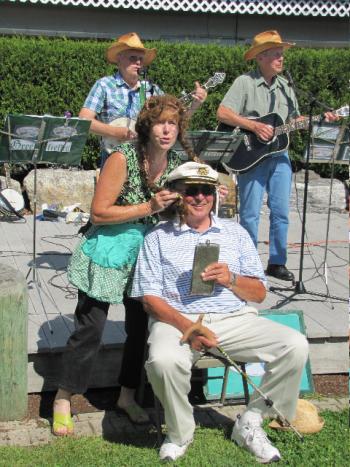 Dick Whittier of Boothbay Harbor volunteers to play a role in a comical song with Debra Arter and the Greenfields at the art fair.