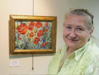 Svetlana Beattie shown with one of her paintings at the FIRST Bank in Boothbay Harbor. 