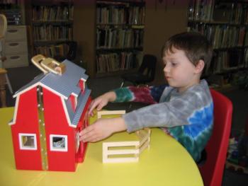 Owen checks out the newly acquired barn and farm animals in the Children’s Room of the Wiscasset Public Library. The barn was a gift from Papa Geppetto’s Workshop on Front Street in Bath.