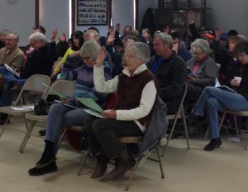 Alna voters make their wishes known during town meeting at the fire station. Below: Alna Assistant Fire Chief Roger Whitney discusses the department’s regulatory requirements, as residents debate fire officials’ raises at the annual town meeting March 16. SUSAN JOHNS/Wiscasset Newspaper Alna voters make their wishes known during town meeting at the fire station. SUSAN JOHNS/Wiscasset Newspaper