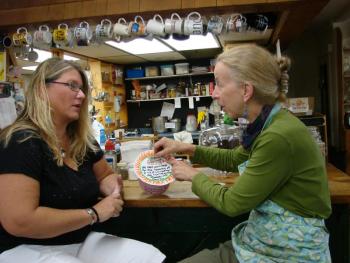 Teresa Simpson, left, talks with Alna Store co-owner Amy Preston, as Preston adds to a donation canister to help cover the stray dog’s medical costs. SUSAN JOHNS/Wiscassest Newspaper