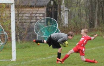 Midcoast striker Will Shafer charges after the ball during the second half of play at Clifford Playground. Shaffer scored on a breakaway in the opening seconds of the match. Below: Simon Spear shows perfect kicking form at midfield. SUE MELLO/Boothbay Register Midcoast striker Will Shafer charges after the ball during the second half of play at Clifford Playground. Shaffer scored on a breakaway in the opening seconds of the match. SUE MELLO/Boothbay Register
