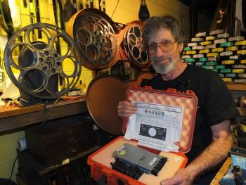 Jason Sheckley holds a new digital movie “The Great Gatsby,” while posing amongst old film equipment. The theater underwent a digital conversion on May 8. RYAN LEIGHTON/Boothbay Register