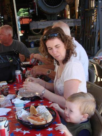 Annie Coderre and son Jacob Jones, 21 months, of Montreal, Quebec, enjoy lunch off the grill at the Wiscasset, Waterville & Farmington Railway Museum's picnic and yard sale August 11, day two of the weekend event. SUSAN JOHNS/Wiscasset Newspaper