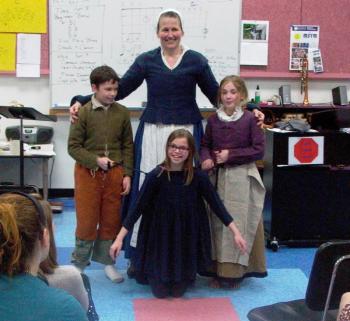 Plimoth Plantation Living History presenter Vicki Oman demonstrates clothing from the early 17th century with the help of Bristol School fifth and sixth graders, prior to their Colonial Overnight visit to Plimoth Plantation. Students are, from left, Dawson Wall, Liza Cheney and Madison Opert. Courtesy of Peggy Farrell
