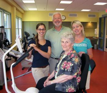 Miriam Wade sits on a new exercise bike designed specifically for people with Parkinson’s that she donated to the St. Andrews Campus of LincolnHealth. Standing behind Miriam are Occupational Therapist Lisa Castonguay, left, who offers LSVT BIG therapy to help people with Parkinson’s move better, Speech Therapist Jennifer Bryce, who offers LSVT LOUD therapy to help people with Parkinson’s overcome speech problems associated with the disorder, and Physical Therapist Jim Stevens, Site Supervisor of the St. Andrews Wellness Department. Courtesy of LincolnHealth