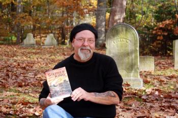 NEAR BOOTHBAY HARBOR’S Pear Street Cemetery on Oct. 30, Glenn Chadbourne holds a just-published collector’s edition of Stephen King’s “Carrie,” illustrated by Chadbourne. SUZI THAYER/Boothbay Register